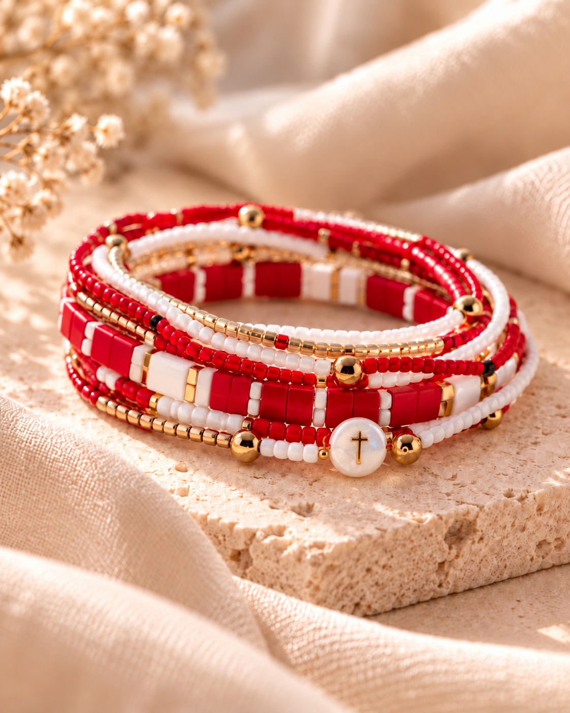 The Scarlet Edit: scarlet, ivory and gold-tone bracelet strands with a round white cross bead on warm stone.